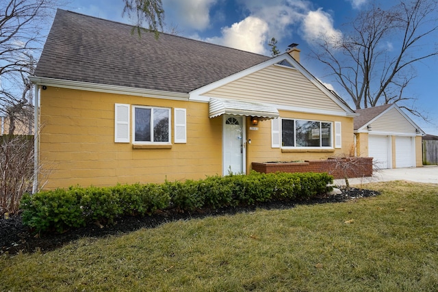 view of front of property featuring a front yard, a garage, roof with shingles, and a chimney