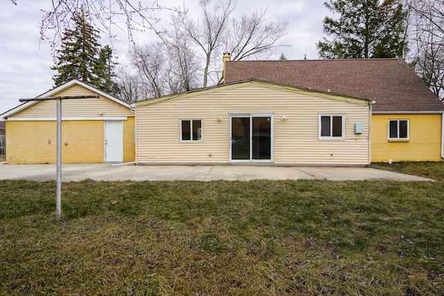 rear view of property with a lawn, a shingled roof, a chimney, and a patio area