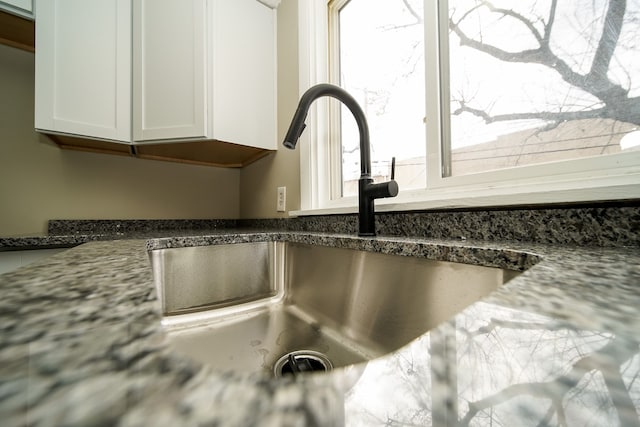 room details with a sink, dark stone counters, and white cabinets