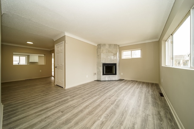 unfurnished living room featuring a high end fireplace, visible vents, light wood finished floors, and baseboards