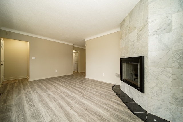 unfurnished living room featuring visible vents, wood finished floors, crown molding, baseboards, and a tile fireplace