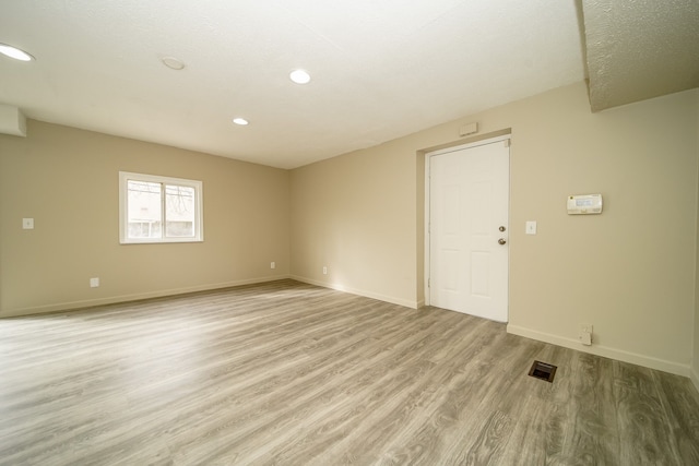 empty room with recessed lighting, light wood-style floors, visible vents, and baseboards