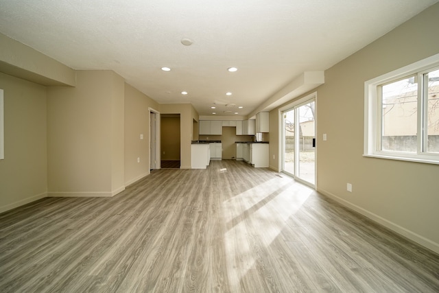 unfurnished living room featuring recessed lighting, light wood-type flooring, and baseboards