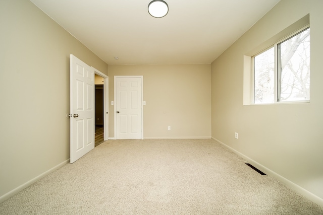 spare room with visible vents, baseboards, and light colored carpet