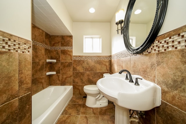 bathroom featuring wainscoting, toilet, and tile walls