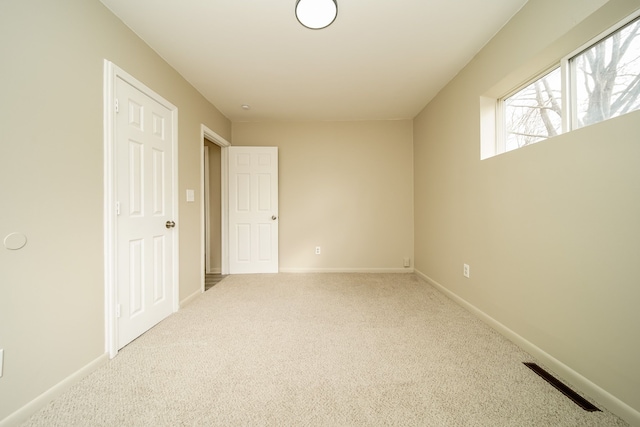 carpeted empty room featuring visible vents and baseboards