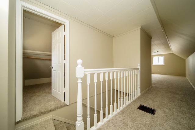 corridor with an upstairs landing, visible vents, lofted ceiling, and carpet