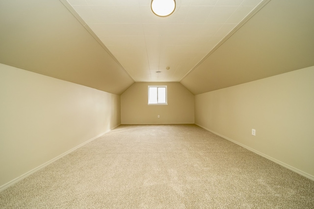 bonus room with light colored carpet, baseboards, and lofted ceiling