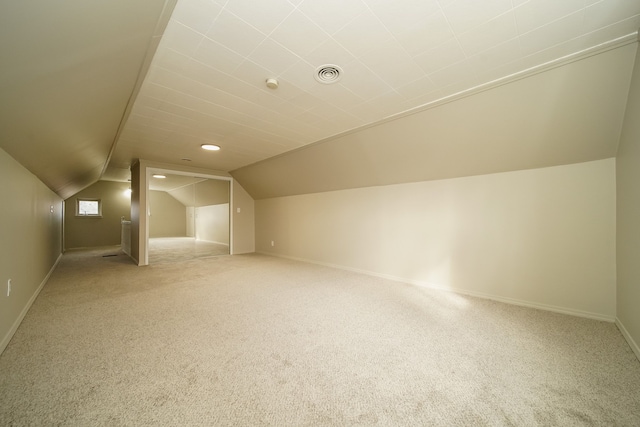 bonus room with vaulted ceiling, baseboards, visible vents, and light carpet