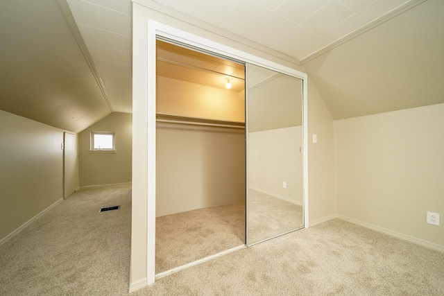 unfurnished bedroom featuring vaulted ceiling, carpet, visible vents, and a closet