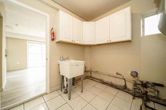 clothes washing area featuring light tile patterned floors and baseboards