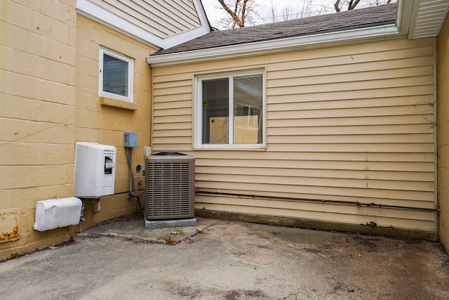 exterior space featuring cooling unit and roof with shingles