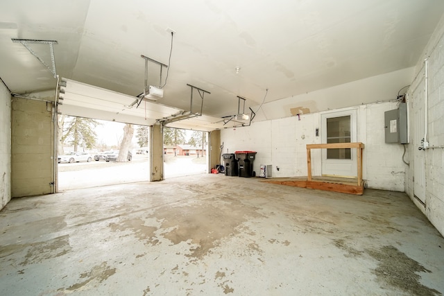 garage with concrete block wall, electric panel, and a garage door opener