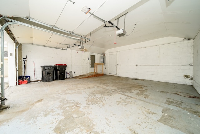 garage featuring electric panel, concrete block wall, and a garage door opener