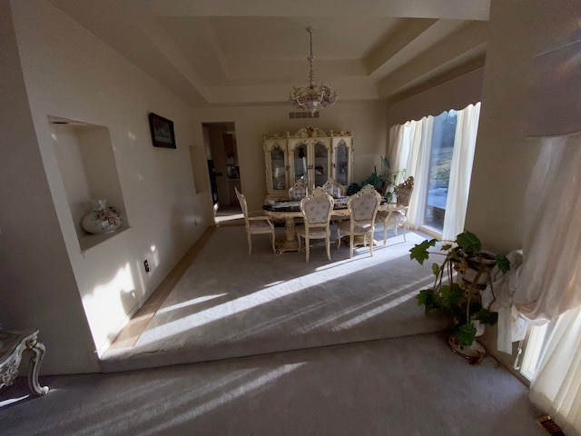 carpeted dining space with visible vents, an inviting chandelier, and a tray ceiling