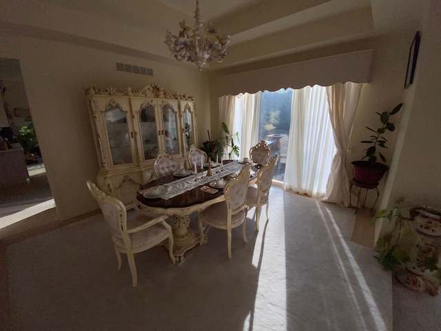 dining room with visible vents, a raised ceiling, and a notable chandelier