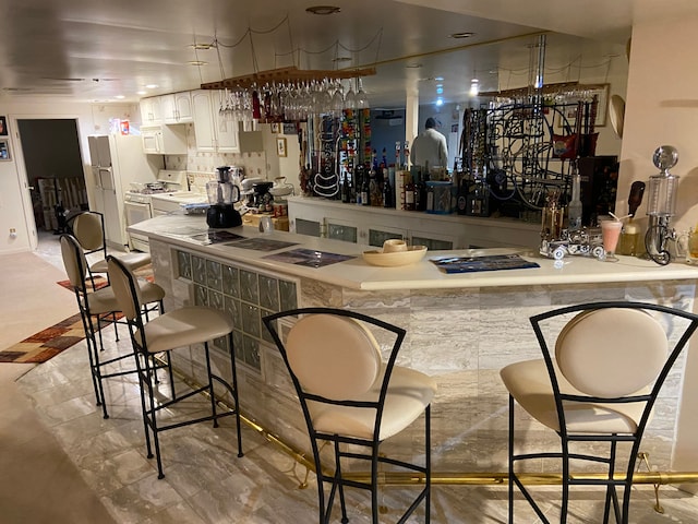 bar featuring white appliances, bar area, and tasteful backsplash