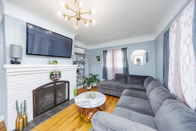 living area featuring a chandelier, a brick fireplace, and wood finished floors