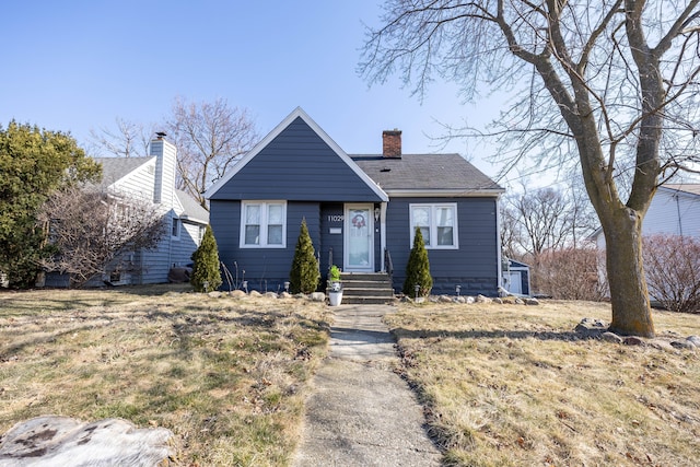 bungalow-style house with a chimney and a shingled roof