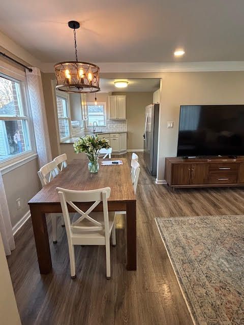 dining area with a chandelier, baseboards, dark wood-style flooring, and ornamental molding