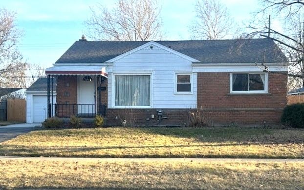 view of front of home featuring aphalt driveway, brick siding, and a front lawn