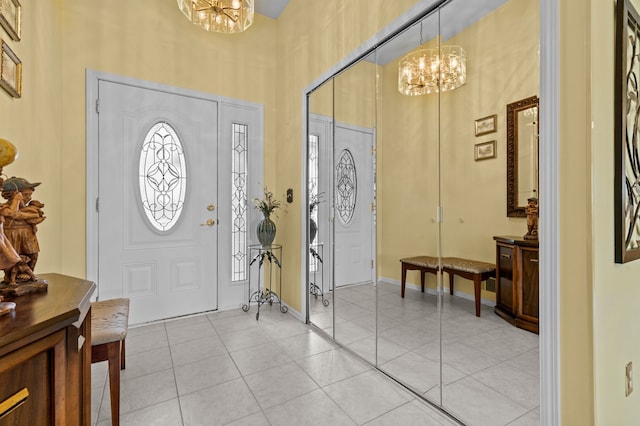 entrance foyer featuring light tile patterned floors, a high ceiling, an inviting chandelier, and baseboards