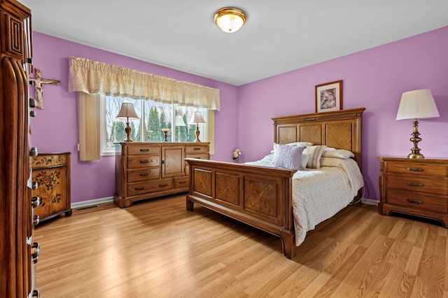 bedroom with visible vents, light wood-style flooring, and baseboards