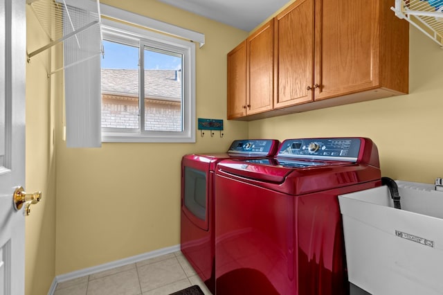 laundry area with light tile patterned floors, cabinet space, a sink, baseboards, and washing machine and dryer