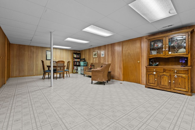 interior space featuring wooden walls, visible vents, and a drop ceiling