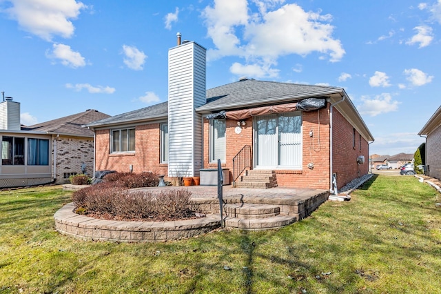 rear view of house with a chimney, a yard, entry steps, and brick siding