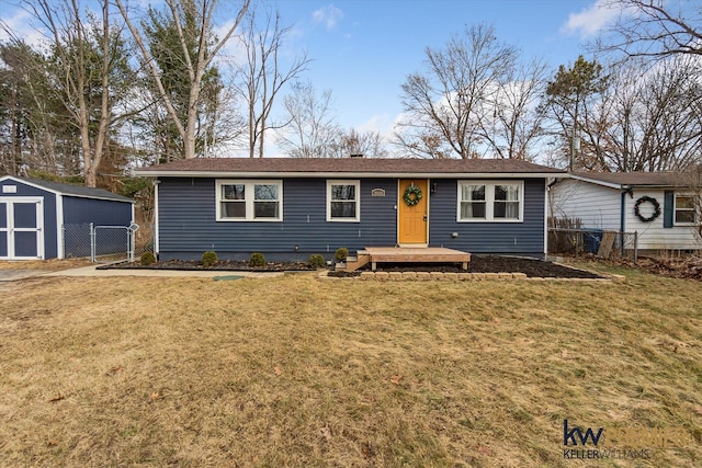 ranch-style home featuring a shed, an outbuilding, a front lawn, and fence