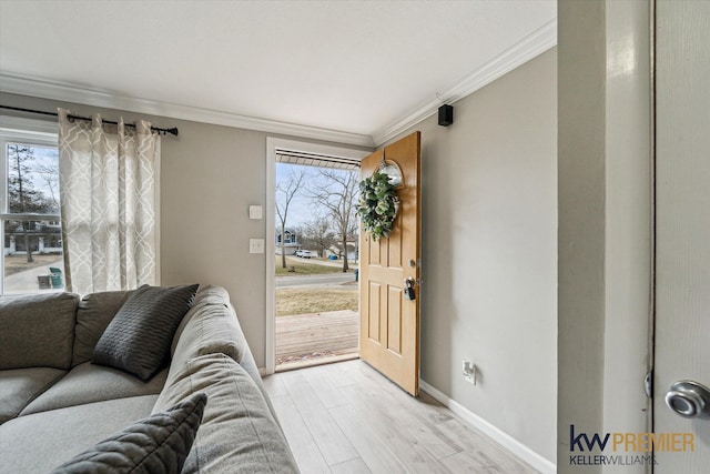 interior space featuring light wood finished floors, a healthy amount of sunlight, baseboards, and ornamental molding