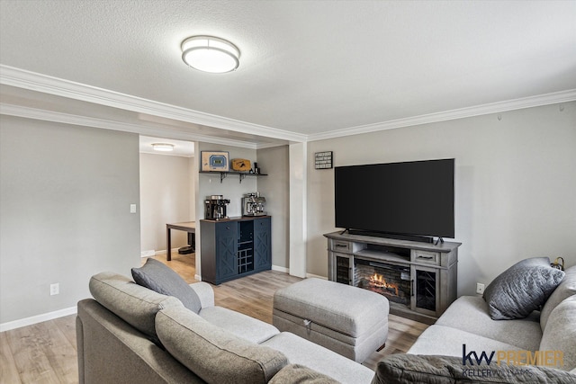 living area with baseboards, crown molding, and light wood-style floors