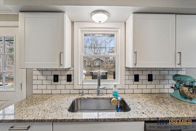 kitchen featuring decorative backsplash, white cabinetry, a wealth of natural light, and a sink