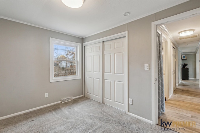 unfurnished bedroom with a closet, visible vents, baseboards, and ornamental molding