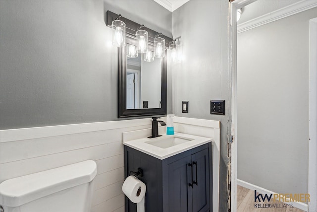 half bathroom featuring toilet, vanity, and crown molding