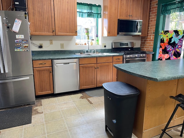 kitchen with dark countertops, light floors, stainless steel appliances, and a sink