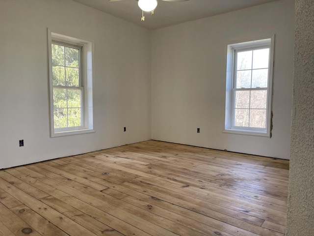 spare room featuring a wealth of natural light, a ceiling fan, and hardwood / wood-style flooring