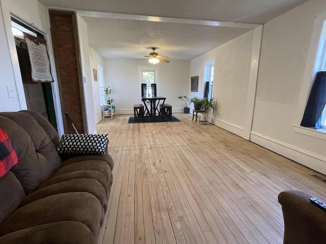 living area featuring visible vents, ceiling fan, baseboards, and light wood-style floors