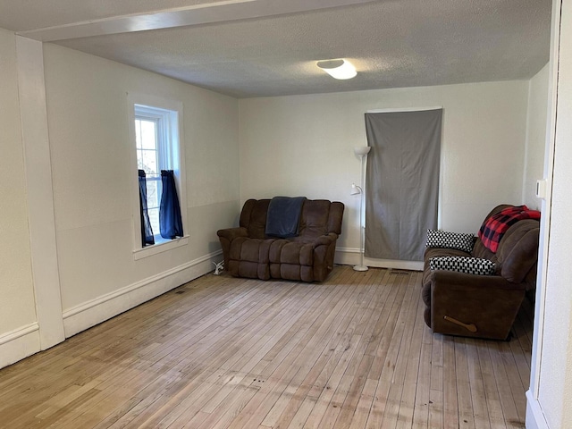 living area with light wood finished floors, a textured ceiling, and baseboards