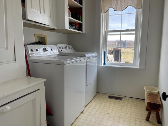 laundry area featuring cabinet space, light floors, visible vents, and washing machine and clothes dryer