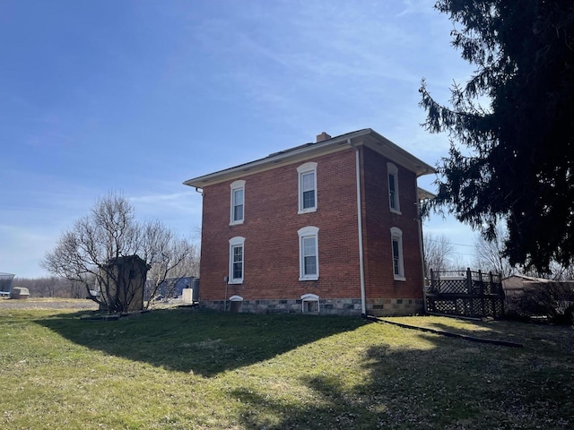 view of property exterior with a yard, brick siding, and a chimney