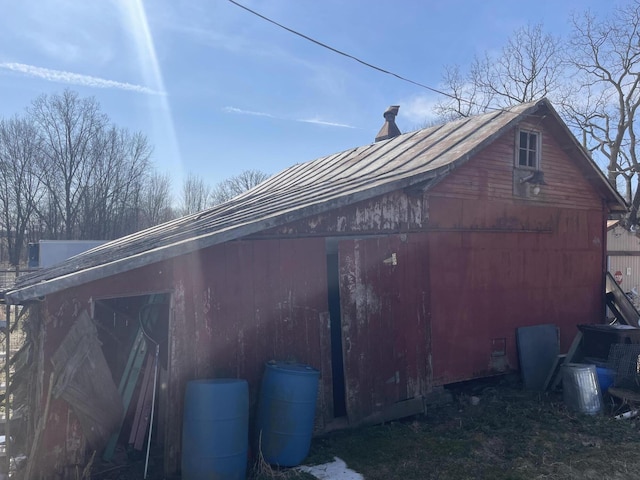 view of property exterior featuring metal roof, an outbuilding, a barn, and a standing seam roof