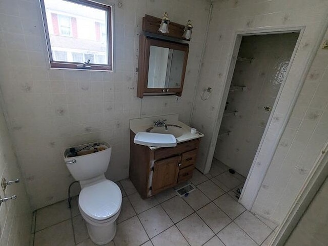 half bath with tile patterned floors, toilet, and vanity