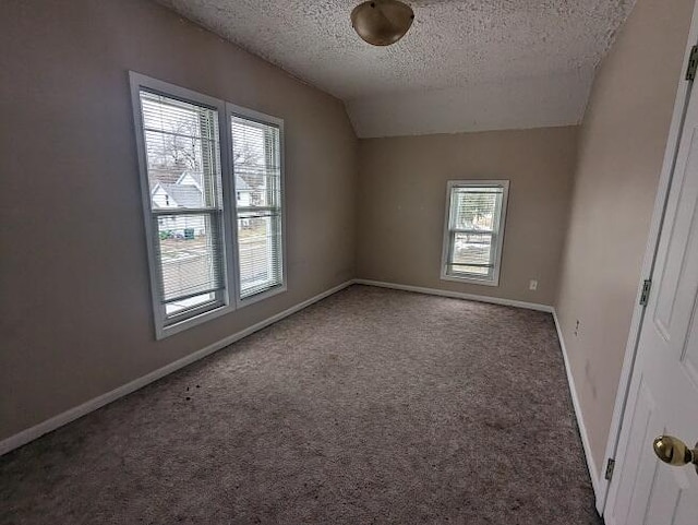 carpeted spare room featuring baseboards, lofted ceiling, and a textured ceiling