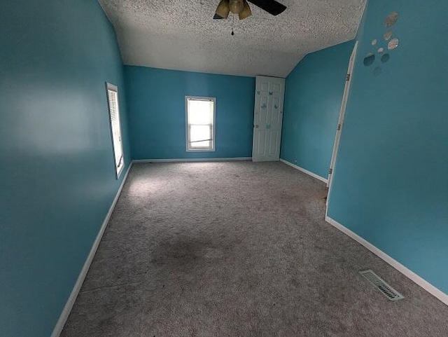 carpeted empty room with visible vents, baseboards, ceiling fan, lofted ceiling, and a textured ceiling