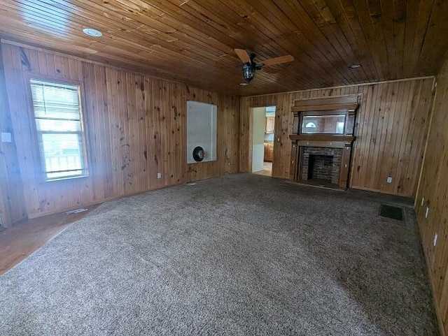 unfurnished living room with carpet flooring, wood walls, a brick fireplace, and wood ceiling