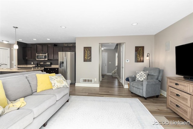 living room with baseboards, recessed lighting, visible vents, and light wood-type flooring