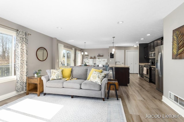 living area featuring visible vents, recessed lighting, baseboards, and light wood-style floors