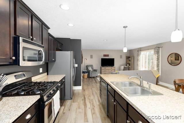 kitchen with open floor plan, appliances with stainless steel finishes, light countertops, and a sink